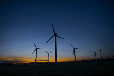 Power generators of windmills at shadow sunset - wind turbine on field at sunset