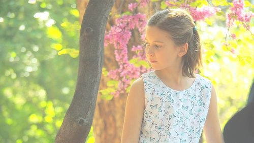 Thoughtful girl against trees looking away