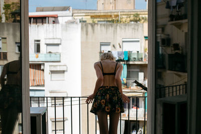 Rear view of woman standing by window in building