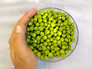 High angle view of hand holding green peas