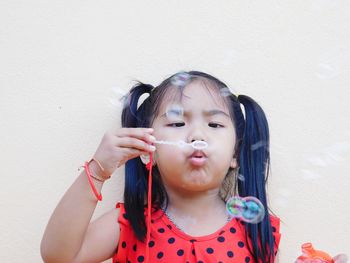 Girl blowing bubbles against wall