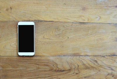 Directly above shot of smart phone on wooden table