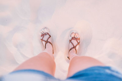 Low section of woman standing on sand