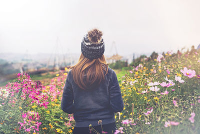 Rear view of woman standing on field against sky