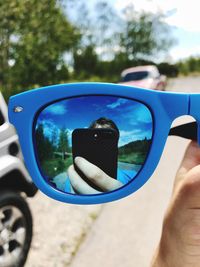 Reflection of man on sunglasses against blue sky