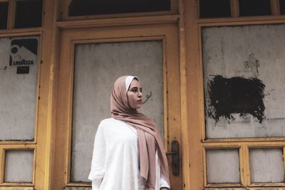 Portrait of woman standing against building