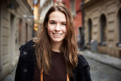 Portrait of smiling young woman in alley at city