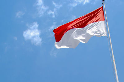 Low angle view of flag against blue sky