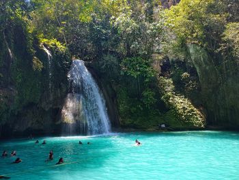 People swimming in water at rocks