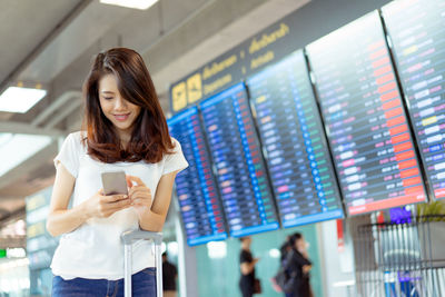 Portrait of a smiling young woman using phone