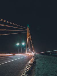 Light trails on bridge against sky at night