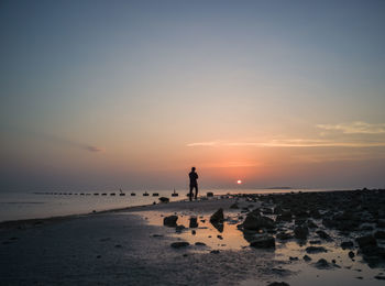 Man standing on beach against sky during sunset