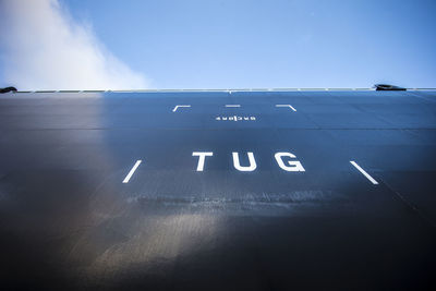Low angle view of tug text on ship against sky