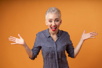 Portrait of happy woman screaming against orange background