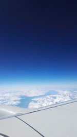 Aerial view of snowy landscape against blue sky