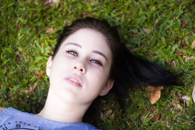 Portrait of beautiful young woman lying on grassy field