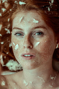 Close-up portrait of young woman with freckles on face