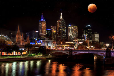 Illuminated buildings in melbourne city with super moon reflected over the yarra river at night