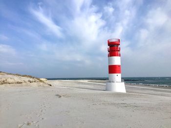 Lighthouse by sea against sky