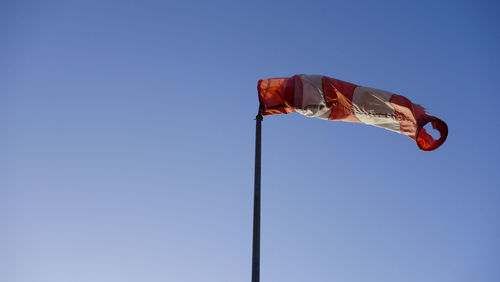 Low angle view of flag against clear blue sky