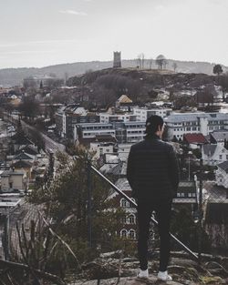 Rear view of man looking at cityscape against sky