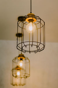 Close-up of illuminated light bulb hanging from ceiling