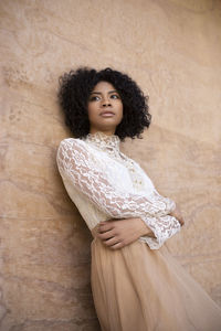 Portrait of young woman standing against wall