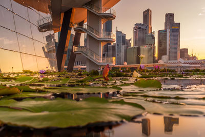 Reflection of buildings in lake against sky in city