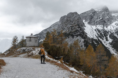 Female hiker wearing winter clothes, standing on path with amazing view in mountains