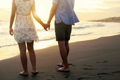 Low section of couple walking on beach