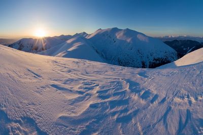 Scenic view of snowcapped mountains against sky during sunset