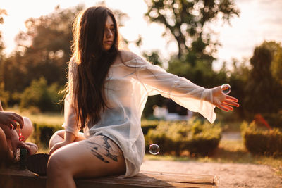 Young women playing with bubbles in park during summer at sunset