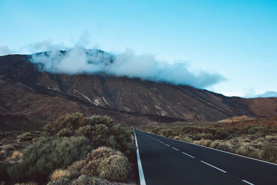 Scenic view of road by mountains against sky