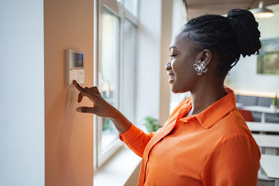 Side view of young woman looking through window
