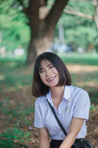 Portrait of smiling young woman sitting at park