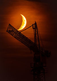 Low angle view of crane against sky during sunset