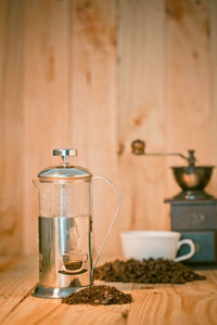 Close-up of grinder with coffee beans and jar on wooden table