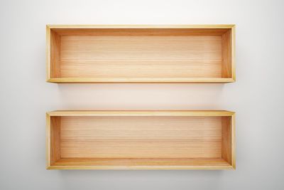 Empty wooden shelves on white wall