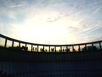 Silhouette of people against cloudy sky at sunset