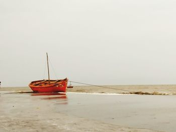 Boat moored on beach against clear sky