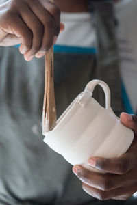 Close up of hands of the female ceramic artist glazing a cup