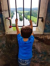 Rear view of boy looking through window