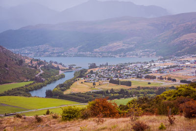 Scenic view of townscape by mountains against sky