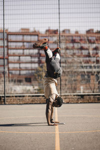 Man with legs apart doing acrobatic activity on basketball court