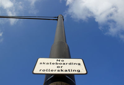 Low angle view of warning sign on pole against blue sky