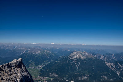 Aerial view of snowcapped mountains against clear blue sky