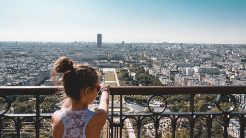 Rear view of girl looking at cityscape against clear sky