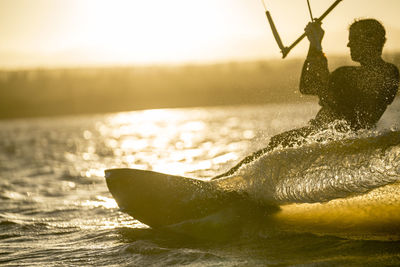 Young male athlete kiteboarding at sunset in la ventana, baja california, mexico