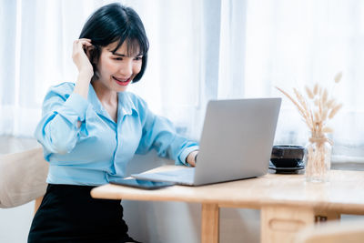 Businesswoman using laptop at desk in office