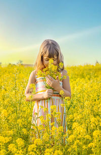 Girl smelling flowers in field